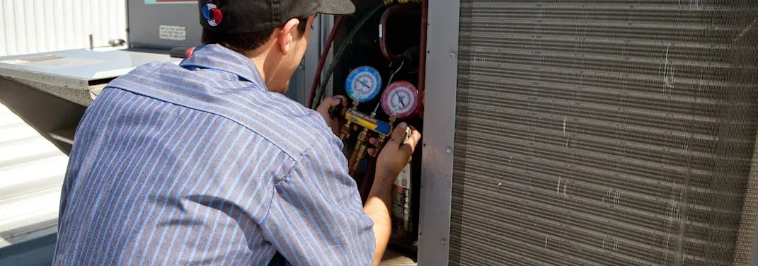 HVAC technician servicing a condenser unit in Muscatine