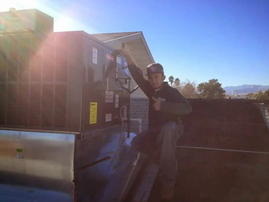 HVAC technician performing Air Duct Cleaning on a rooftop unit in Muscatine